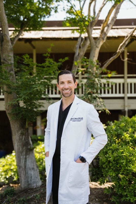 Portrait of Dr. Marre standing outdoors in a white lab coat at the dental office