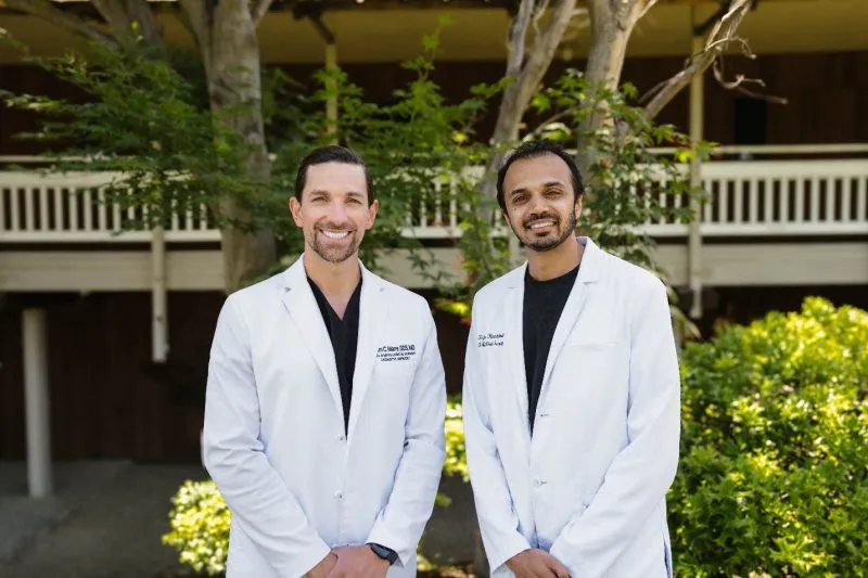 Group portrait of the doctors standing outdoors in white lab coats at the dental office