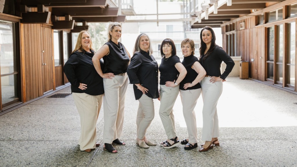 Dental team members posing together outdoors at the dental office entrance