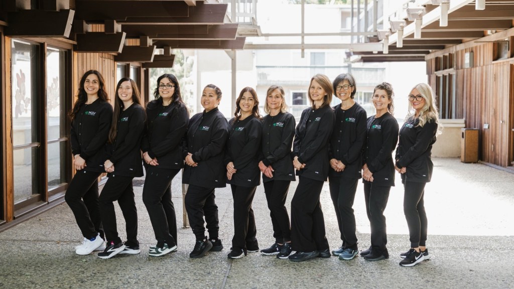 Group portrait of the dental office team standing together in professional uniforms at the practice entrance
